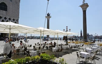 27/06/2020
Venezia: ombrelloni in Piazza San Marco per garantire il distanziamento

Mossa anti-crisi dei caffè storici. I gestori assicurano: saranno il meno impattanti possibile. Ma non mancano le polemiche.

In piazza San Marco a Venezia sono stati montati i primi ombrelloni che copriranno gli spazi davanti ai locali, allargati per favorire la sistemazione in sicurezza dei tavolini in base alle norme di sicurezza sul coronavirus. Le prime coperture sono state allestite davanti al Caffè Florian. Poi le squadre di operai sono passate al Quadri, al Lavena e concluderanno ai caffè Aurora e Chioggia, davanti a Palazzo Ducale.  I manufatti sono tutti uguali, a pianta quadrata e dello stesso color bianco avorio delle "lunette" che coprono gli archi delle Procuratie. Il disegno, concordato con l'Associazione commercianti di Piazza San Marco, è ispirato ai teloni raffigurati nei quadri del Canaletto dedicati all'area marciana. Gli ombrelloni resteranno fino al 31 ottobre, una concessione della Soprintendenza, che in passato aveva rifiutato simili proposte, per agevolare i caffè che stanno cercando di riprendersi dalla chiusura.