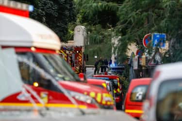 Police officers stand next to rescue vehicles near the bar "Le Ramus" (unseen) where a motorist drove onto the terrace of a cafe, leaving several injured, in Paris on July 17, 2024. A police source told AFP that the investigation into the car that ploughed into the terrace of a bar in Paris on July 17, killing one and injuring six people, is "currently focusing on a road accident". (Photo by IAN LANGSDON / AFP) (Photo by IAN LANGSDON/AFP via Getty Images)