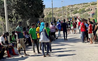 Migranti in attesa di essere caricati sugli autobus per raggiungere il porto dove verranno imbarcati su navi militari e traghetti di linea, Lampedusa, 14 settembre 2023. ANSA/ELIO DESIDERIO