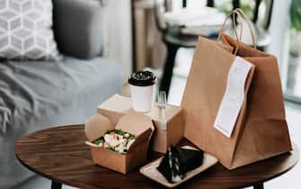 Assorted fresh and healthy takeaway meals delivered at home, with healthy grilled chicken vegetable salad, Japanese style rice ball / onigiri and a cup of coffee freshly served on the coffee table