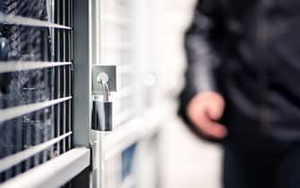 Burglar or thief and storage with lock in basement of condo apartment building. Suspicious man, intruder and criminal. Door with padlock for security.