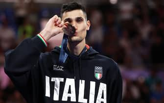 Bronze medallist Italy's Simone Alessio celebrates on the podium during the medal ceremony for the taekwondo men's -80kg competition of the Paris 2024 Olympic Games at the Grand Palais in Paris on August 9, 2024. (Photo by David GRAY / AFP)