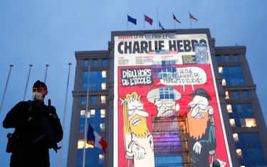 epa08762561 A police officer stands by as cartoons from French satirical newspaper Charlie Hebdo are projected onto buildings in central Montpellier in France, 21 October 2020. The cartoons of Prophet Mohammed were projected to pay tribute to the teacher Samuel Paty who was assassinated in Conflans-Sainte-Honorine. On 16 October French school teacher Samuel Paty was decapitated by 18-year-old attacker named Abdoulakh Anzorov who has been shot dead by policemen. Paty was a history teacher who had recently shown caricatures from Charlie Hebdo newspapers of the Prophet Mohammed in class.  EPA/GUILLAUME HORCAJUELO
