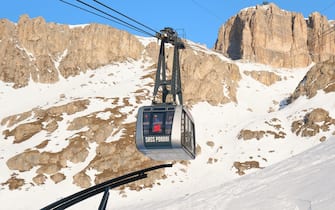 Dolomites, Italy - January 24, 2020: Cable car Sass Pordoi (Funivia Pass Pordoi) arriving in the lower embarking station, with people waiting to go up