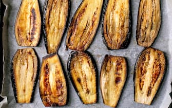 Sliced grilled eggplants on baking paper. Top view food background