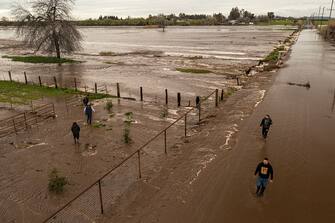 PORTERVILLE, CA - MARCH 10: In an aerial view, people look at the flood waters of Deer Creek on March 10, 2023 near Porterville, California. Another in a series of atmospheric river storms from the Pacific Ocean has brought a warm rain to the region, which is falling on top of, and melting, large areas of snow in the Sierra Nevada Mountains, increasing the risk of floods at lower elevations. This years destructive and deadly storms have produced heavy rains and a near-record snowpack in the Sierras, which provides water for millions of Californians. As a result of one of Californias wettest winters on record, most of the state has gotten relief from years of drought. (Photo by David McNew/Getty Images)