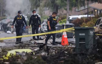 Investigators look through the site where a small plane crashed into a San Diego, California, residential street on May 22, 2025. The Federal Aviation Authority said a Cessna 550 crashed at around 3:45 am local time. The neighborhood is close to the Montgomery-Gibbs Executive Airport. The crash left a "gigantic debris field" and damaged some 15 homes and parked cars, ABC News quoted the San Diego assistant fire chief as saying. (Photo by Sandy Huffaker / AFP)