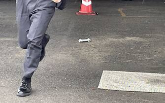 A cylinder-shaped object (C), believed to have been thrown during Japan's Prime Minister Fumio Kishida's campaign, is seen on the ground in Wakayama on April 15, 2023. - Kishida was evacuated from a port in Wakayama after a blast was heard, but he was unharmed in the incident, local media reported on April 15. (Photo by JIJI Press / AFP) / Japan OUT (Photo by STR/JIJI Press/AFP via Getty Images)