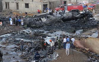 Pakistani rescuers gather on the site where a cargo plane crashed after taking off from Karachi on November 28, 2010. At least eight people were killed when a Russian-made cargo plane crashed in a fireball seconds after taking off from Karachi on November 28, a spokesman for Pakistan's civil aviation authority said. The death toll was expected to rise, with an unknown number of labourers feared killed when the Ilyushin IL-76, bound for the Sudanese capital Khartoum, slammed into airport buildings in the Pakistani business capital.  AFP PHOTO/Asif HASSAN (Photo by Asif HASSAN / AFP) (Photo by ASIF HASSAN/AFP via Getty Images)