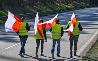 25 February 2024, Poland, Slubice: Participants in a demonstration carrying the national flag of Poland walk along the closed Autostrada A2 (European route 30) towards the German-Polish border (Frankfurt/Oder).  The protests by Polish farmers, which have been going on for weeks, are directed against EU agricultural policy, but also against the import of cheap agricultural products from Ukraine. Photo: Patrick Pleul/dpa (Photo by Patrick Pleul/picture alliance via Getty Images)