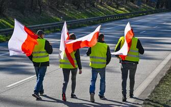 25 February 2024, Poland, Slubice: Participants in a demonstration carrying the national flag of Poland walk along the closed Autostrada A2 (European route 30) towards the German-Polish border (Frankfurt/Oder).  The protests by Polish farmers, which have been going on for weeks, are directed against EU agricultural policy, but also against the import of cheap agricultural products from Ukraine. Photo: Patrick Pleul/dpa (Photo by Patrick Pleul/picture alliance via Getty Images)