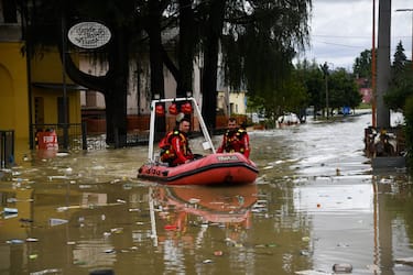 TOPSHOT - Volunteer firefighters ride their dinghy across a street flooded by the river Savio in the Ponte Vecchio district of Cesena, central eastern Italy, on May 17, 2023. Trains were stopped and schools were closed in many towns while people were asked to leave the ground floors of their homes and to avoid going out, and five people have died after the floodings across Italy's northern Emilia Romagna region. (Photo by Alessandro SERRANO / AFP) (Photo by ALESSANDRO SERRANO/AFP via Getty Images)