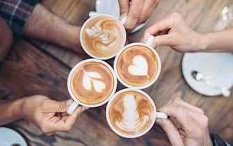 Above view of hands holding cappuccino cups