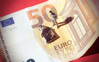 Miniature business man inside a 50 euros banknote and a symbol of a house.