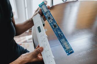 Close-up of unrecognizable black woman replacing refrigerator's user interface control board