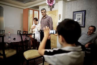Iranian lawyer Nasrin Sotoudeh (L) speaks on the phone next to her husband Reza Khandan (C) as their son, Nima takes their picture at her house in Tehran on September 18, 2013, after being freed following three years in prison. Sotoudeh told AFP she was in "good" physical and psychological condition, and pledged to continue her human rights work. Her release came a week before Irans new moderate President Hassan Rowhani, who has promised more freedoms at home and constructive engagement with the world, travels to New York to attend the United Nations General Assembly.  AFP PHOTO/BEHROUZ MEHRI        (Photo credit should read BEHROUZ MEHRI/AFP via Getty Images)