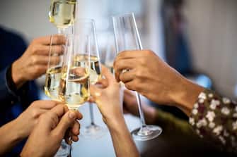 Close-up of hands toasting champagne flutes during dinner party at home