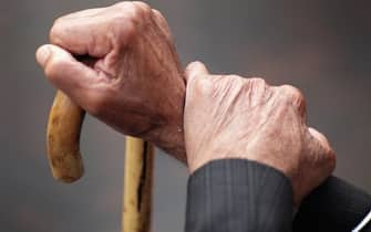 mani di persona anziana su bastone