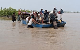 TOPSHOT - People with their belongings wade through the flood affected area of Chanda Singh Wala village in Kasur district on August 22, 2023. Around 100,000 people have been evacuated from flooded villages in Pakistan's Punjab province, an emergency services representative said on August 23. (Photo by Arif ALI / AFP) (Photo by ARIF ALI/AFP via Getty Images)