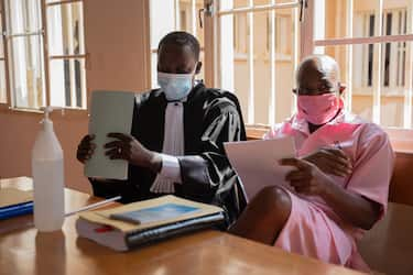 "Hotel Rwanda" hero Paul Rusesabagina (R) in the pink inmate's uniform sits with his lawyer David Rugaza (L) at the Nyarugenge Court of Justice in Kigali, Rwanda, on September 25, 2020. - Paul Rusesabagina, whose actions during the genocide inspired the Oscar-nominated film "Hotel Rwanda", was charged on September 14, 2020, with terrorism and other serious crimes in his first court appearance in Kigali. Rwandan investigators announced last month the surprise arrest of Rusesabagina, a high-profile government critic who had been living abroad for years, to stand trial in his homeland for allegedly creating and sponsoring armed militias. (Photo by Simon Wohlfahrt / AFP) (Photo by SIMON WOHLFAHRT/AFP via Getty Images)