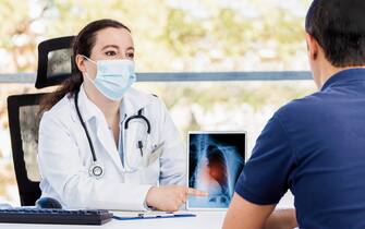 Shot of a young female doctor using a digital tablet during a consultation with a mature man suffering from long covid long