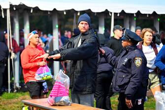 A NYPD officers searches a runner ahead of the 52nd Edition of the New York City Marathon on November 5, 2023. (Photo by ANGELA WEISS / AFP)