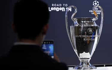 A man takes a picture of the UEFA Champions League trophy ahead of the 2023-2024 UEFA Champions League football tournament round of 16 draw at the House of European Football in Nyon, on December 18, 2023. (Photo by Fabrice COFFRINI / AFP) (Photo by FABRICE COFFRINI/AFP via Getty Images)