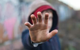 dramatic portrait of a little homeless boy, dirty hand, poverty, city, street