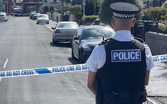 SOUTHPORT, ENGLAND - JULY 29: A police offer stands near a cordon following a stabbing attack on July 29, 2024 in Southport, England. The North West Ambulance Service says they were treating at least eight people for stab injuries after a reported attack near Hart Street. (Photo by Stringer/Getty Images)