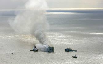 epa10769259 An aerial view shows fire extinguishing operation taking place as smoke rises from the Fremantle Highway cargo ship, in the North Sea, Ameland, the Netherlands,  16 July 202.3 A fire broke out overnight on 26 July on a freighter with 23 crew members onboard, in the North Sea, north of Ameland. According to the Dutch Coast Guard, one person died, and several got hurt.  EPA/Flying Focus BV