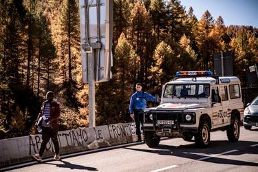 A migrant (L) crosses on foot the border from France into Italy after being driven and pushed back by French Police (R) on October 21, 2018 in the Alpine border town of Claviere, some 100 kilometers west of Turin. - Italy's Interior minister Matteo Salvini sent police on October 20 to Claviere, following an ongoing argument with French authorities over the alleged return of migrants deposed by French police on the Italian side of the border in Claviere. The inscription in Italian on the road's curb reads "Let's take down borders". (Photo by MARCO BERTORELLO / AFP)        (Photo credit should read MARCO BERTORELLO/AFP via Getty Images)