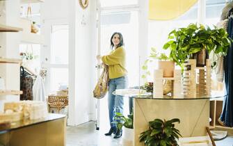 Smiling woman walking through door into boutique