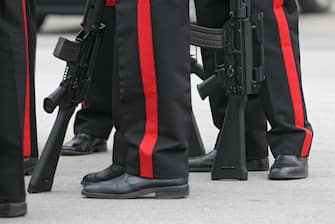 Detail of a group of Carabinieri (national gendarmerie of Italy) while resting with their rifles during a break of a military celebration event.