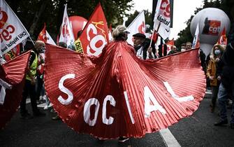 TOPSHOT - A woman holds a banner reading "Social" as people take part in a demonstration called by French unions as part of a nation-wide day for better working conditions and against pensions and unemployement funds reforms, on October 5, 2021 in Bordeaux, southern France. (Photo by Philippe LOPEZ / AFP) (Photo by PHILIPPE LOPEZ/AFP via Getty Images)