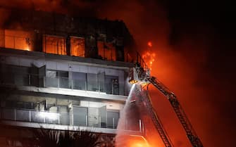 epa11173266 Firemen try to extinguish a fire of a 14-story residential building in Valencia, eastern Spain, 22 February 2024. At least seven people were injured during the ongoing fire, and two people trapped on a balcony were rescued by firefighters.  EPA/MANUEL BRUQUE