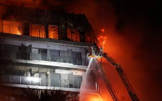 epa11173266 Firemen try to extinguish a fire of a 14-story residential building in Valencia, eastern Spain, 22 February 2024. At least seven people were injured during the ongoing fire, and two people trapped on a balcony were rescued by firefighters.  EPA/MANUEL BRUQUE
