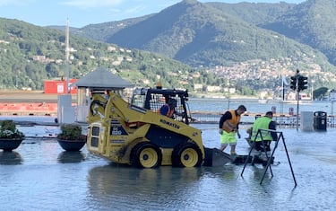 Operai al lavoro in piazza Cavour a Como ricoperta di acqua e detriti esondati dal lago a causa delle copiose piogge dellíaltra sera. Como 5 Agosto 2021. 
ANSA / MATTEO BAZZI