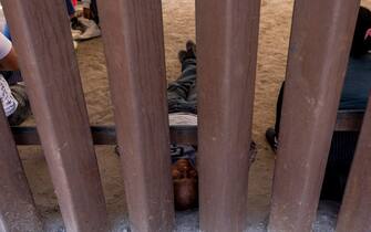 epa10620053 A migrant sleeps in shade behind the border wall while waiting to be brought by Border Patrol officers to a processing center along the border of Mexico and the United States, in Yuma, Arizona, USA, 10 May 2023. A significant increase in the number of migrant crossings is expected as the COVID-era Title 42 policy, which allowed for a quick expulsion of illegal immigrants, is set to expire on 11 May.  EPA/ETIENNE LAURENT