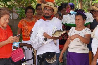 Villagers walk a spectacled caiman (Caiman crocodilus) called "La NiÃ±a Princesa" ("The Princess Girl"), dressed as a bride, before being married to the Mayor in San Pedro Huamelula, Oaxaca state, Mexico on June 30, 2023. This ancient ritual of more than 230 years unites two ethnic groups in marriage to bring prosperity and peace. The spectacled caiman (Caiman crocodilus) is paraded around the community before being dressed as a bride and marrying the Mayor. According to beliefs, this union between the human and the divine will bring blessings such as a good harvest and abundant fishing. (Photo by RUSVEL RASGADO / AFP) (Photo by RUSVEL RASGADO/AFP via Getty Images)