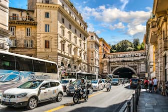 Cars, tour buses, scooters and motorcycles in mid-day traffic near the ancient city walls of Rome, Italy