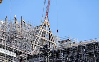 epa10739070 Operators receive the first wood framework at the construction site of Notre Dame Cathedral in Paris, France, 11 July 2023. The oak trusses of the framework are 14 to 16 metres wide and 12 to 13 metres high and weigh between 7 and 7.5 tons, and are the main framework for the Cathedral's spire. Since the fire which devastated the cathedral on 15 April 2019, hundreds of people are working on its reconstruction with the target to reopen the Cathedral before the end of 2024.  EPA/TERESA SUAREZ