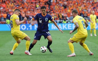 epa11453164 Tijjani Reijnders of the Netherlands (C) in action against Razvan Marin of Romania (L) and Alexandru Cicaldau of Romania (R) during the UEFA EURO 2024 Round of 16 soccer match between Romania and Netherlands, in Munich, Germany, 02 July 2024.  EPA/MOHAMED MESSARA
