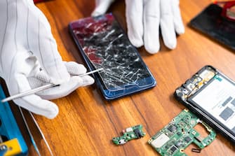 close up shot of technician removing or fixing broken mobile phone display at workshop - concept of skilled worker, professional occupation and small business.