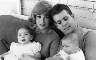 June 1965:  American actor Ryan O'Neal seated with his eight month-old baby son, Griffin, and his wife, actor Joanna Moore, who has their daughter, Tatum, on her lap.  (Photo by Fotos International/Getty Images)