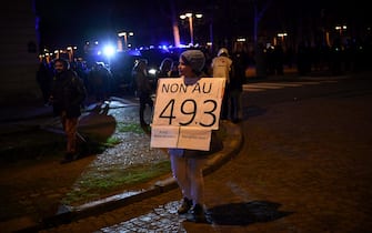 A protestor holds a placard that reads "No to 49,3" during a demonstration at Place Vauban in Paris on March 20, 2023, a few days after the government pushed a pensions reform through parliament without a vote, using the article 49,3 of the constitution. - The French government survived two no-confidence motions in parliament on March 20, 2023 but still faces intense pressure over its handling of a controversial pensions reform. (Photo by Christophe ARCHAMBAULT / AFP)