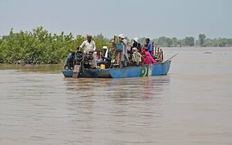 People with their belongings wade through the flood affected area of Chanda Singh Wala village in Kasur district on August 22, 2023. Around 100,000 people have been evacuated from flooded villages in Pakistan's Punjab province, an emergency services representative said on August 23. (Photo by Arif ALI / AFP) (Photo by ARIF ALI/AFP via Getty Images)