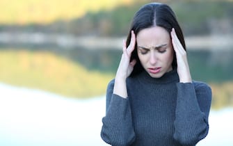 Front view portrait of a woman suffering migraine in a lake