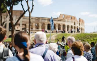 A group of tourists lead by a tour guide in front of the Colosseum / Coliseum in Rome