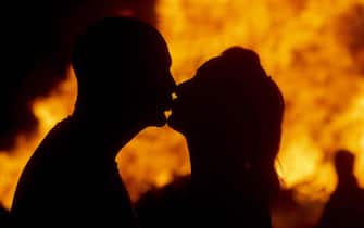 epa10065973 A couple kiss under the glow of the bonfire as Crowds of people celebrate as the Craigyhill bonfire burns in the Craigyhill housing estate, Larne County Antrim, Northern Ireland, 11 July 2022. Members of the public gathered near the huge pile wood tower in the early evening hours to wait for the Craigyhill bonfire to be set on fire. The nighttime bonfire is seen as the start of the 12th of July celebrations in Northern Ireland celebrating King William of Orange's victory over the Catholic King James in the 1690 'Battle of the Boyne'. The unionists' celebrations had always been a controversy between the Protestant and Catholic communities in Northern Ireland.  EPA/MARK MARLOW