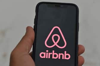An Airbnb logo displayed on a smartphone is seen in L'Aquila, Italy, on september 9th, 2023. Some metropolises and countries are imposing restrictions on Airbnb hosts to protect the hotel industry. (Photo by Lorenzo Di Cola/NurPhoto via Getty Images)